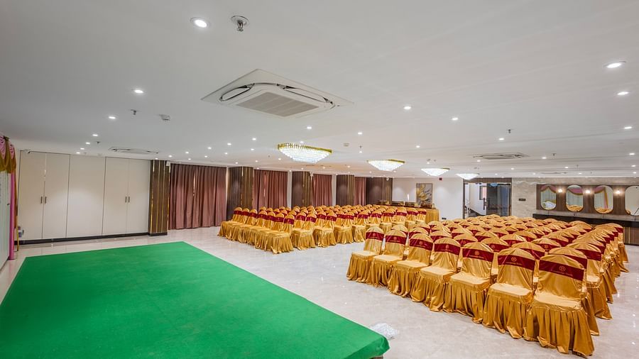 Lemonridge Hotels, KPHB | Banquet hall with an aisle, set up with rows of chairs for a formal event. Clean and maintained space.